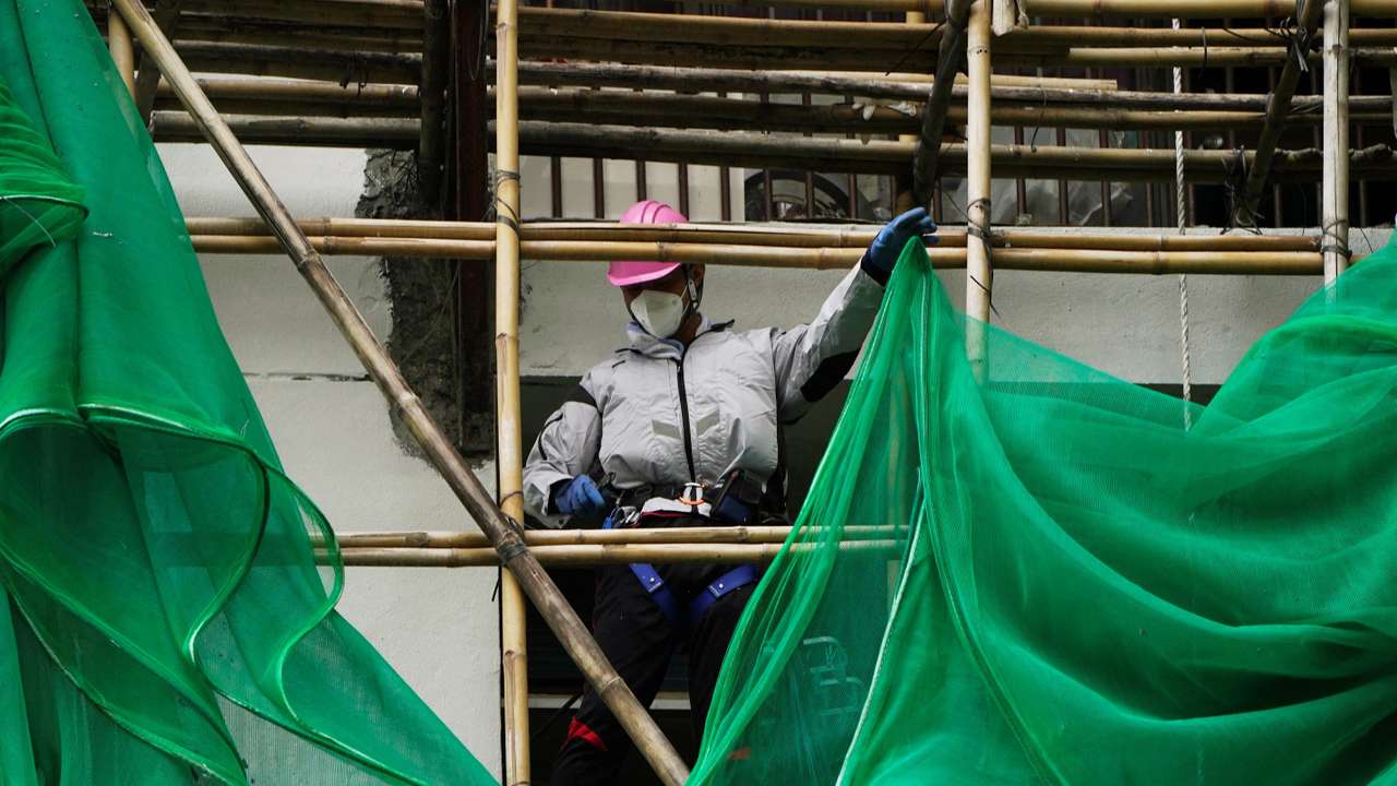 Worker removes scaffolding mesh from a building at Sui Wo Court in Hong Kong