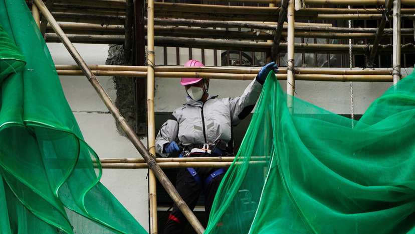 Worker removes scaffolding mesh from a building at Sui Wo Court in Hong Kong
