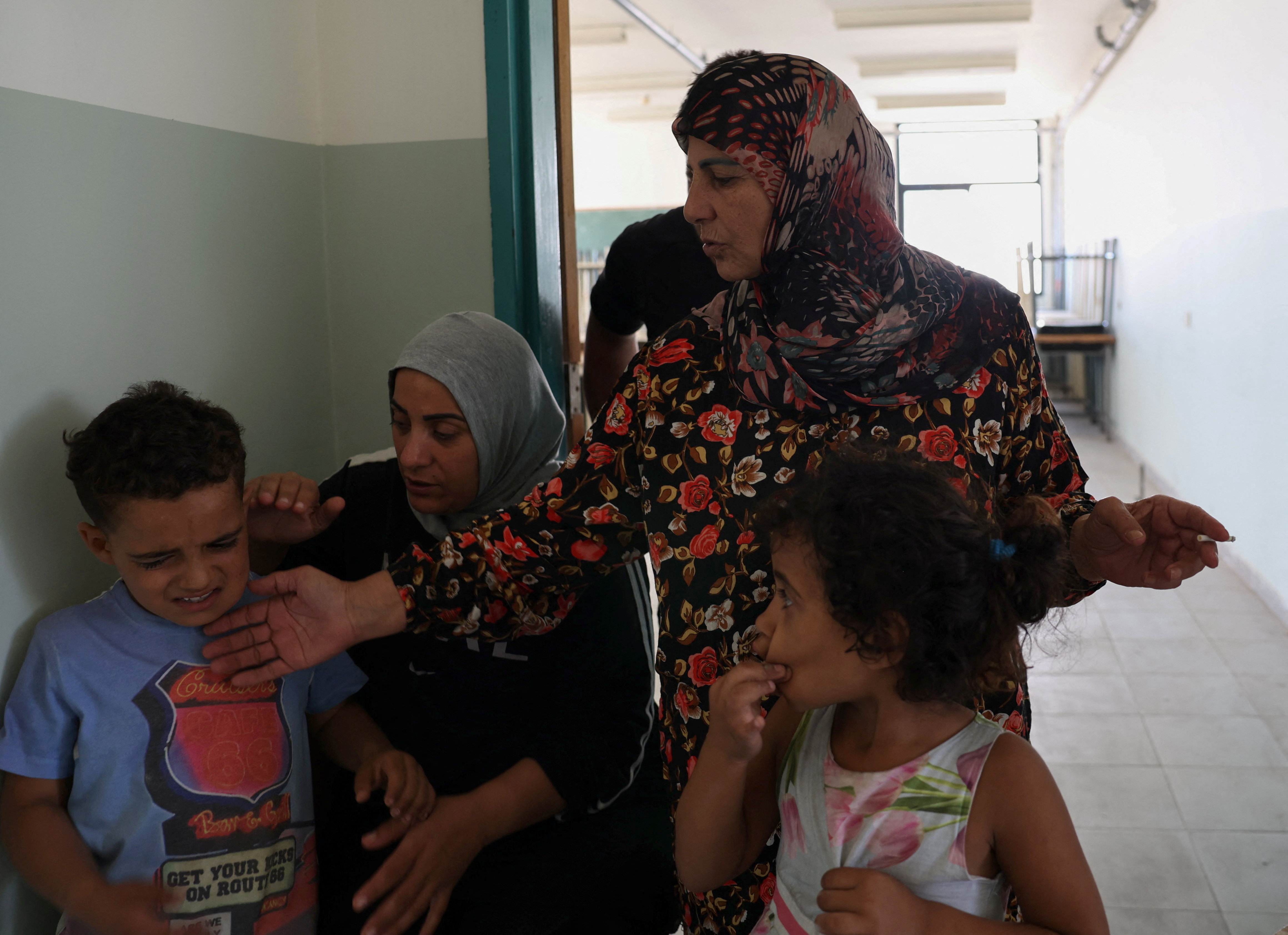 Feryal Mehsen, 58, stands with her family in a hallway, at the Technical Institute of Bir Hassan turned into a shelter in Beirut