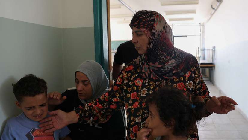 Feryal Mehsen, 58, stands with her family in a hallway, at the Technical Institute of Bir Hassan turned into a shelter in Beirut