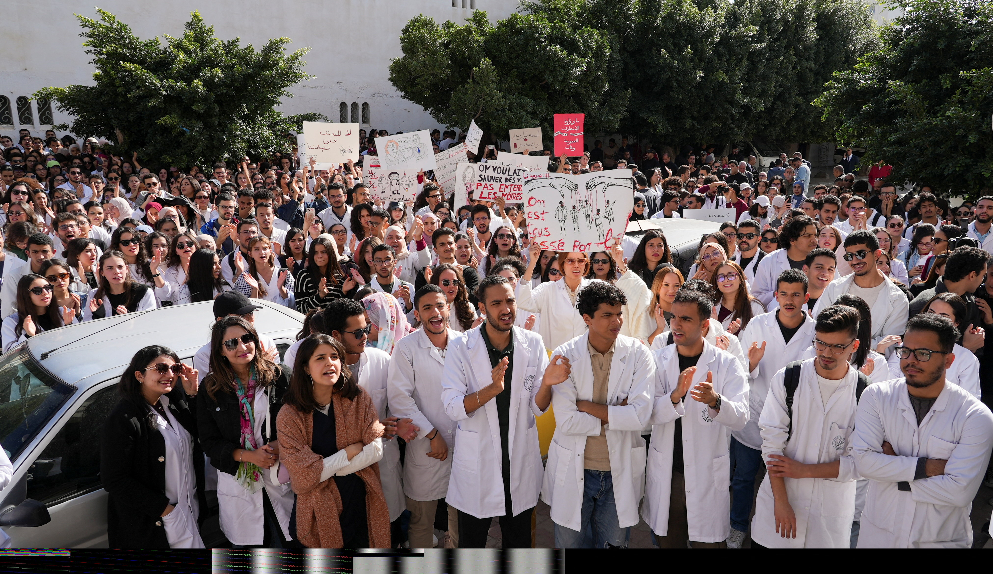 Young doctors gather and hold signs during a protest in Tunis