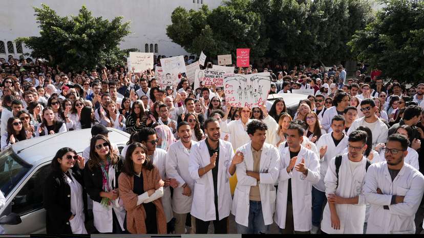 Young doctors gather and hold signs during a protest in Tunis