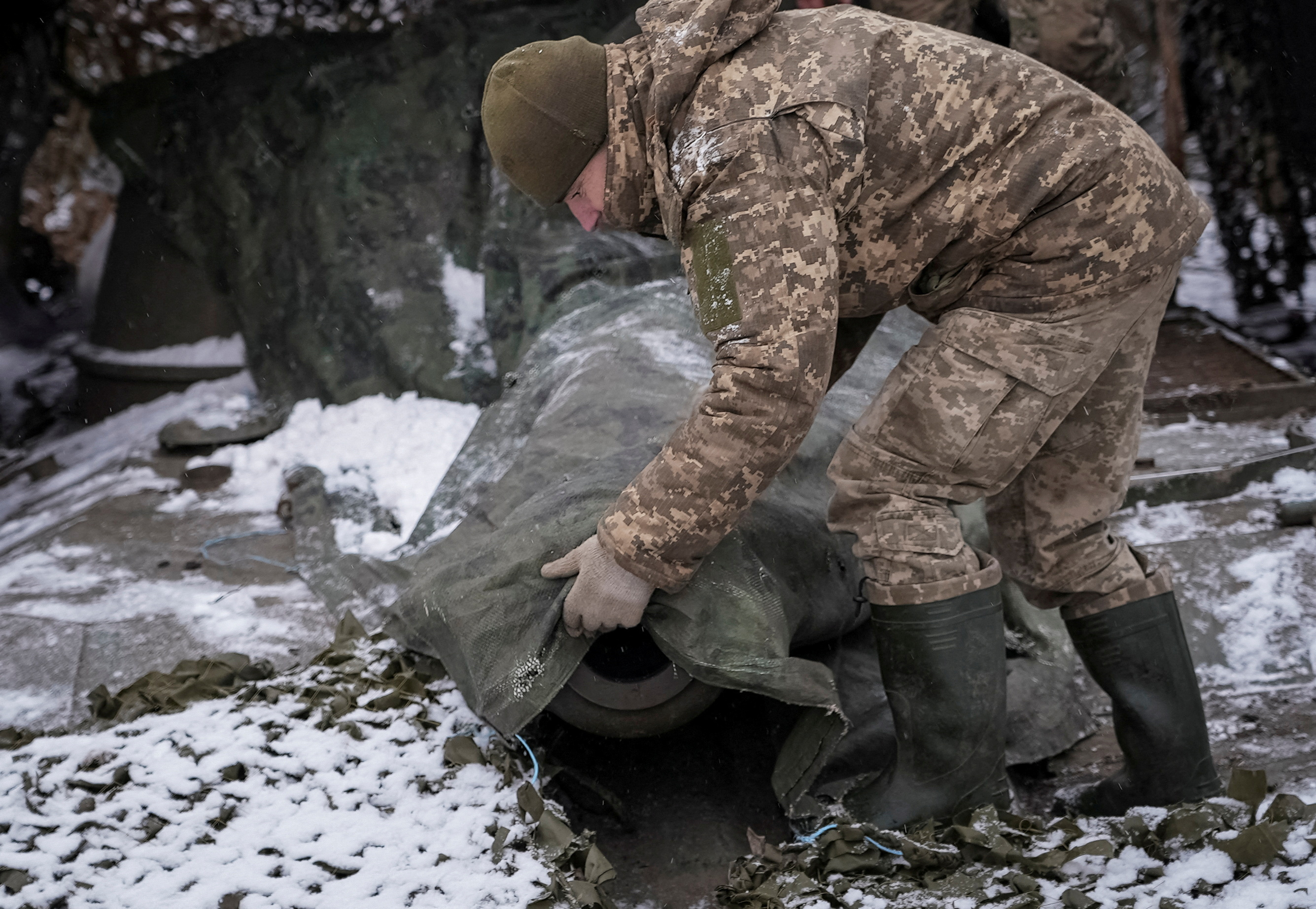 FILE PHOTO: A Ukrainian serviceman camouflages a self propelled howitzer at a front line near the town of Chasiv Yar