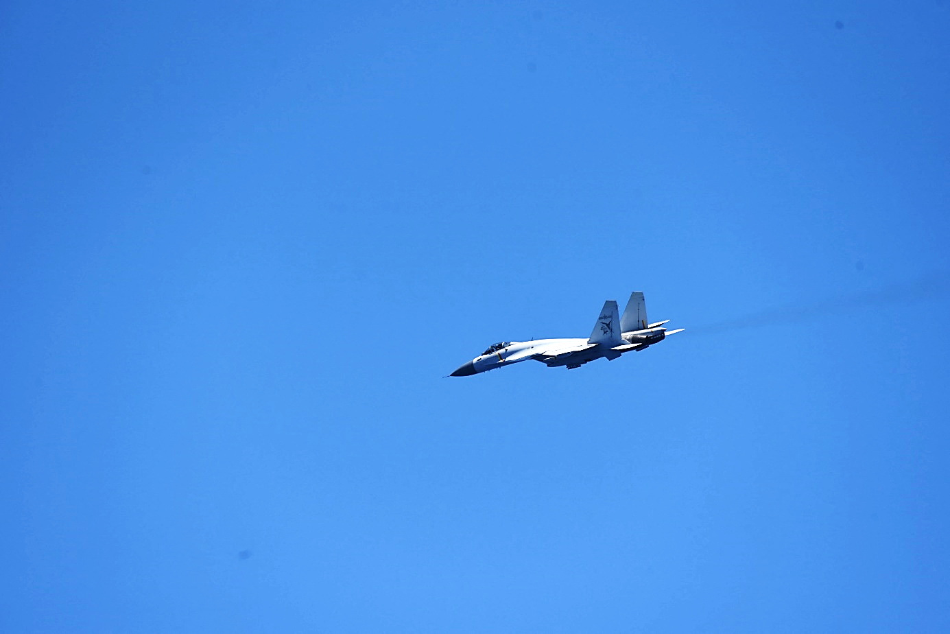 A Chinese Shenyang J-15 fighter aircraft flies near China's Shandong aircraft carrier, over Pacific Ocean waters, south of Okinawa prefecture