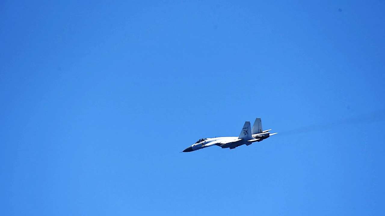 A Chinese Shenyang J-15 fighter aircraft flies near China's Shandong aircraft carrier, over Pacific Ocean waters, south of Okinawa prefecture