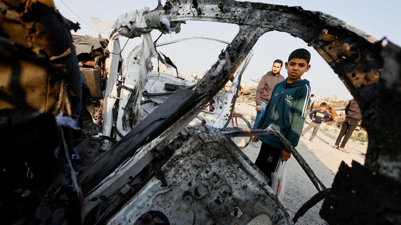 Palestinians inspect the site of an Israeli airstrike targeting a police vehicle in the central Gaza Strip