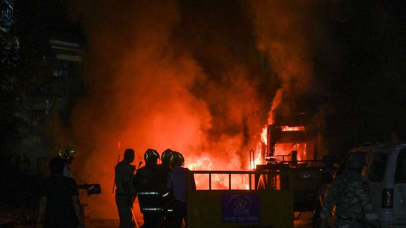 Members of police stand as vehicles burn after clashes erupted due to demands over removal of the tomb of Mughal emperor Aurangzeb, in Nagpur