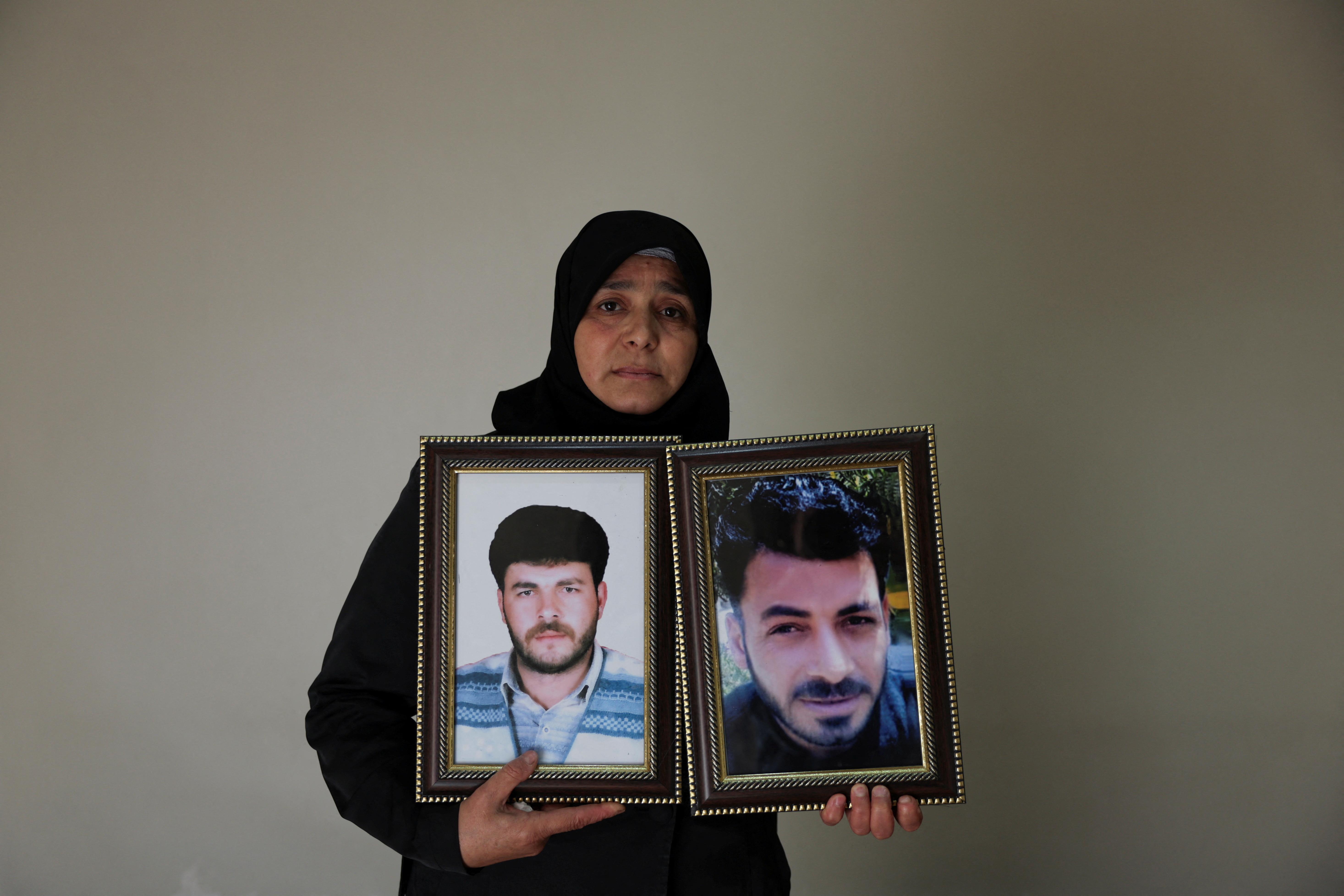 Amina Beqai, holding a photo of her husband and brother, who went missing after they were arrested by security forces under the rule of ousted President Bashar al-Assad, in Damascus