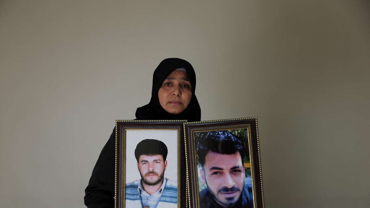 Amina Beqai, holding a photo of her husband and brother, who went missing after they were arrested by security forces under the rule of ousted President Bashar al-Assad, in Damascus