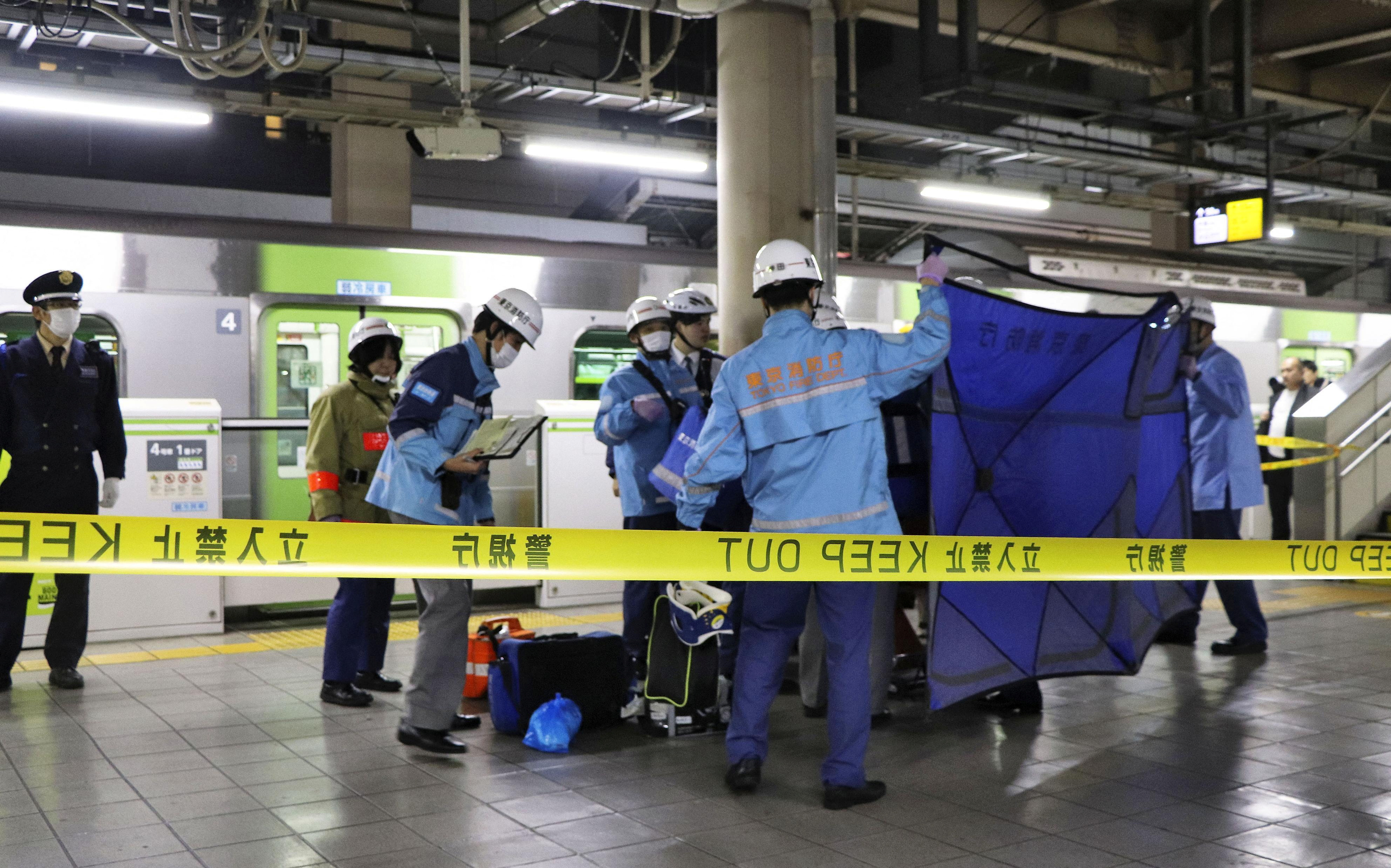 A person who believed to have been stabbed by a knife on the Yamanote loop train line is transported by ambulance members at JR Akihabara Station in Tokyo