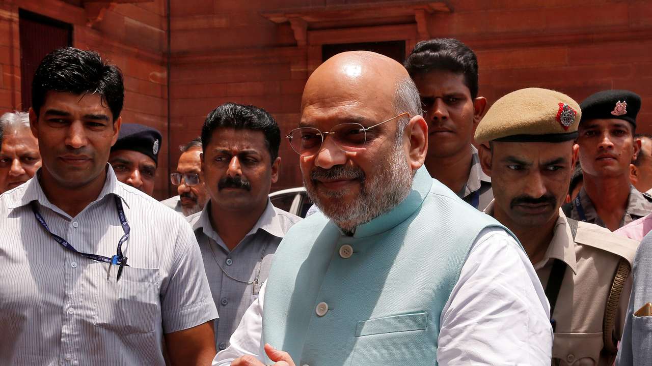India's newly appointed Home Minister Amit Shah greets the media upon his arrival at the home ministry in New Delhi