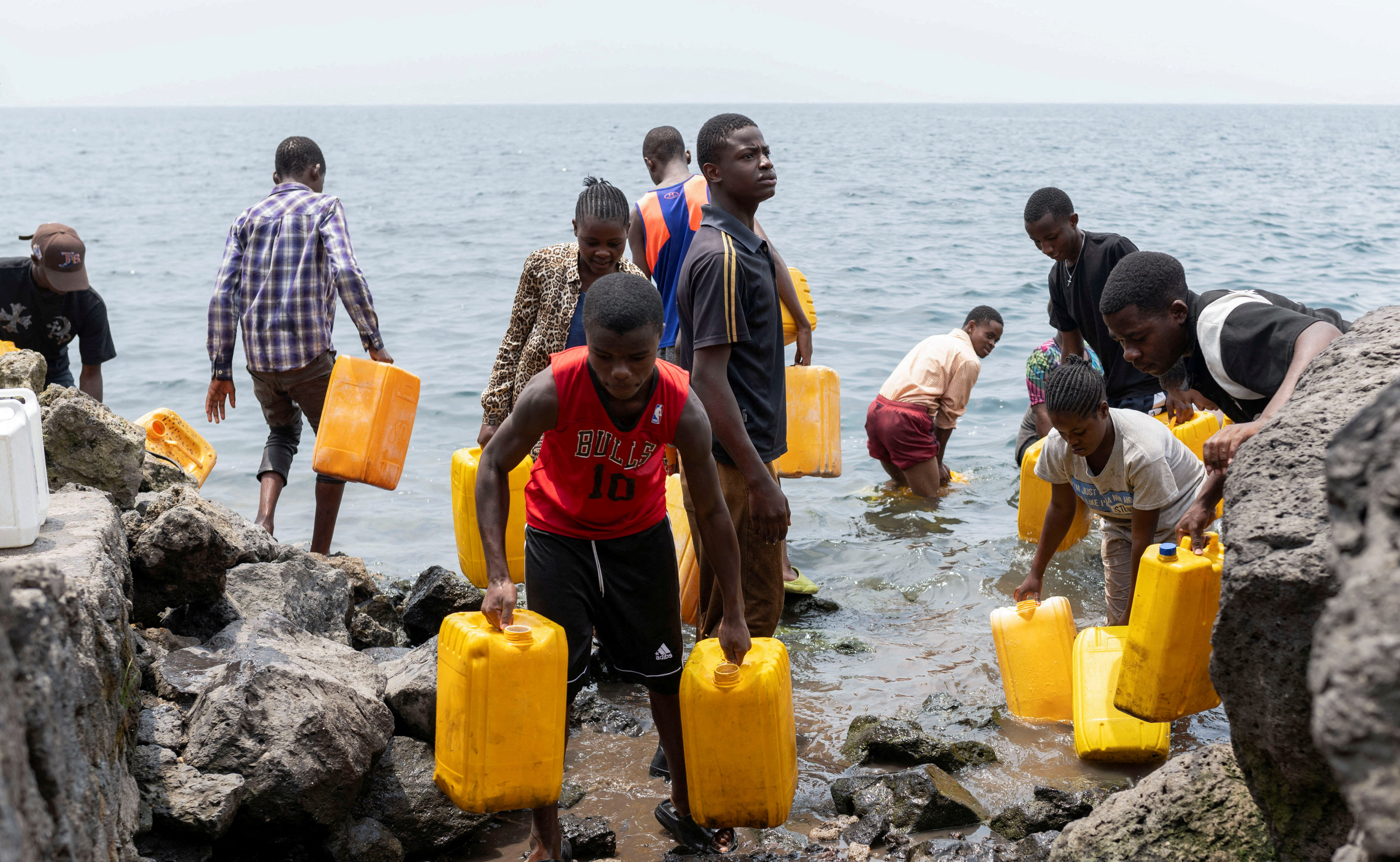 Civilians draw water from Lake Kivu after the town was taken by M23 rebels, in Goma,