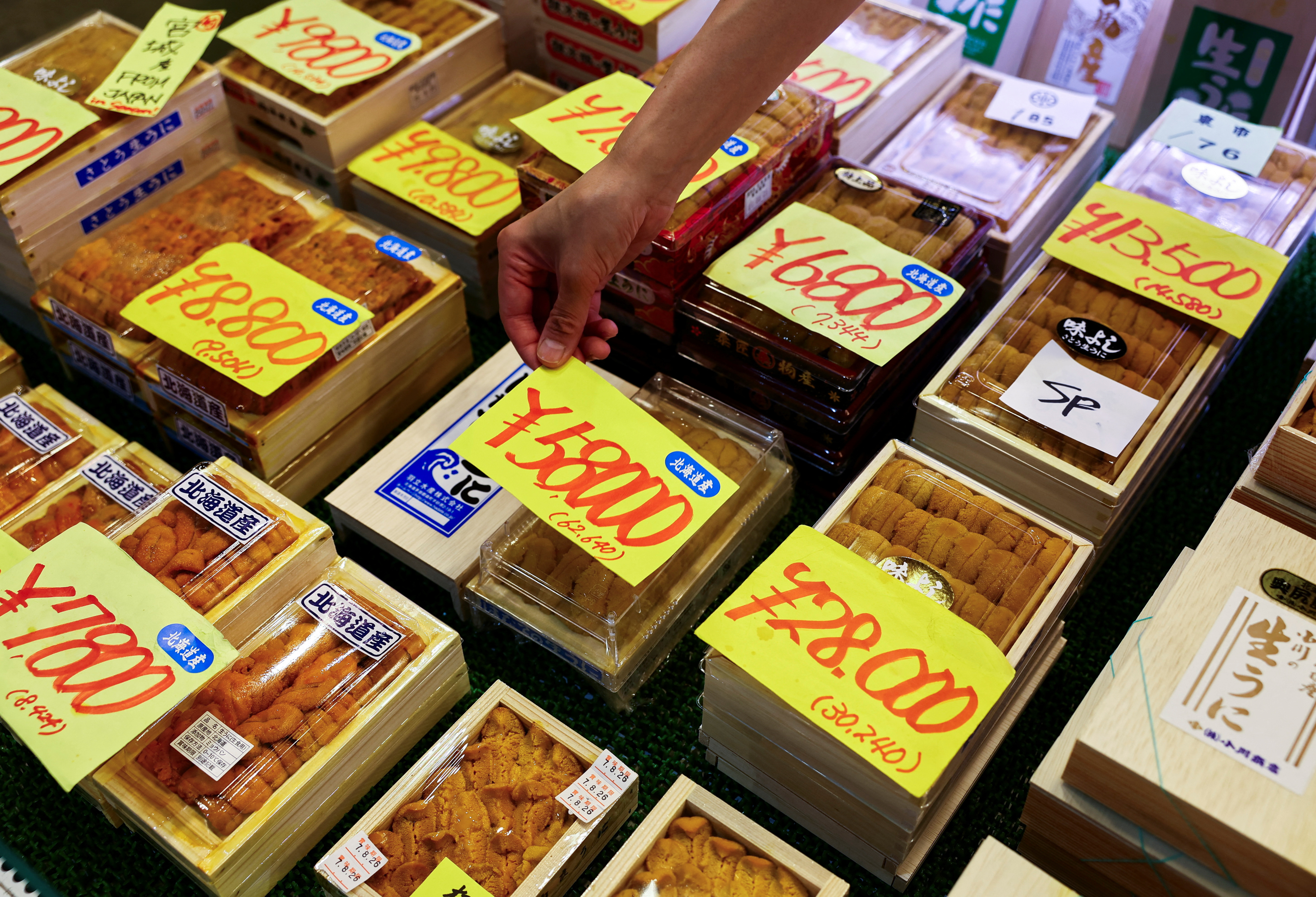 Employee at a wholesaler puts a price tag on a package of sea urchins from Hokkaido at Tsukiji Outer Market in Tokyo