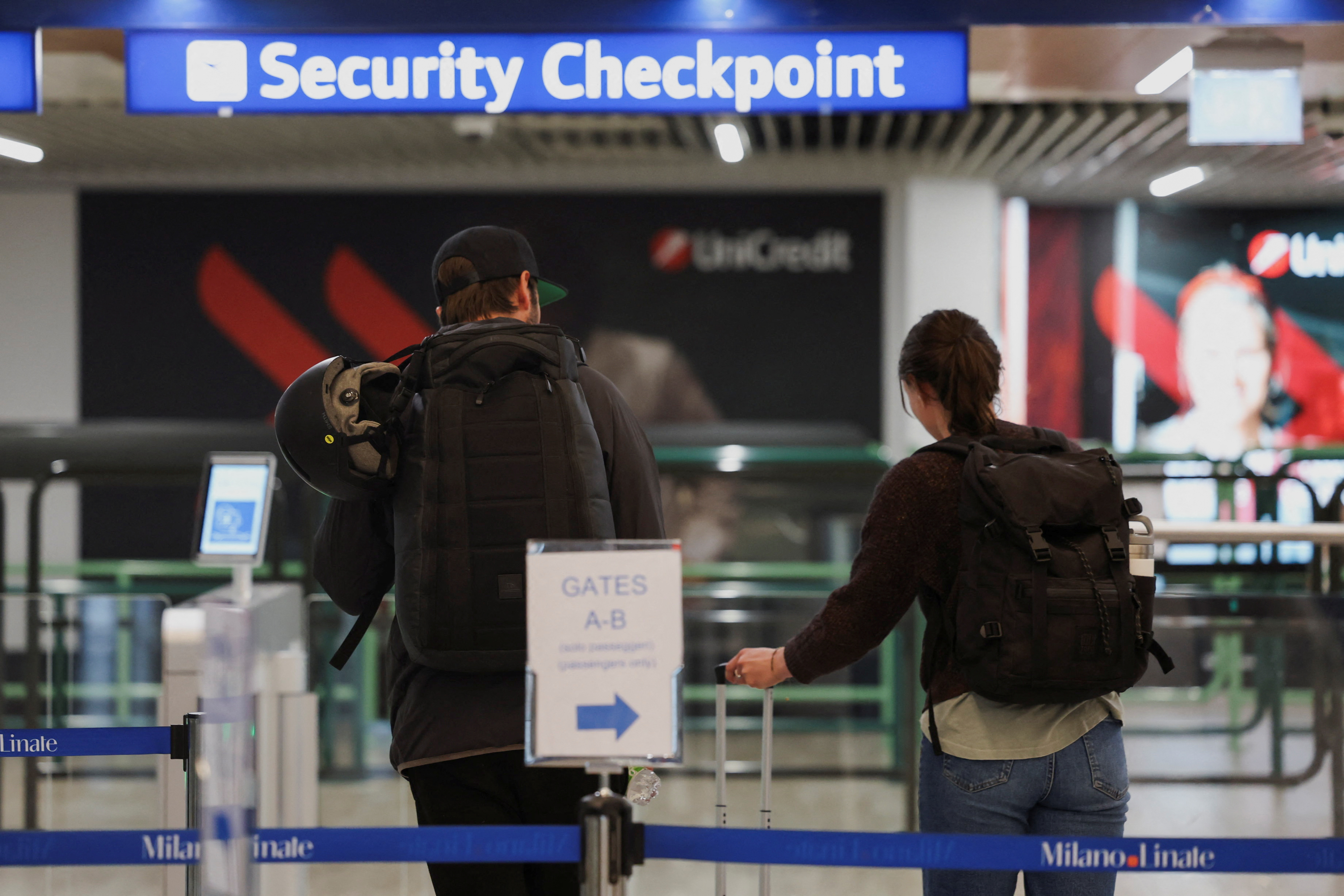 People walk next to a document verification checkpoint at Linate Airport in Milan
