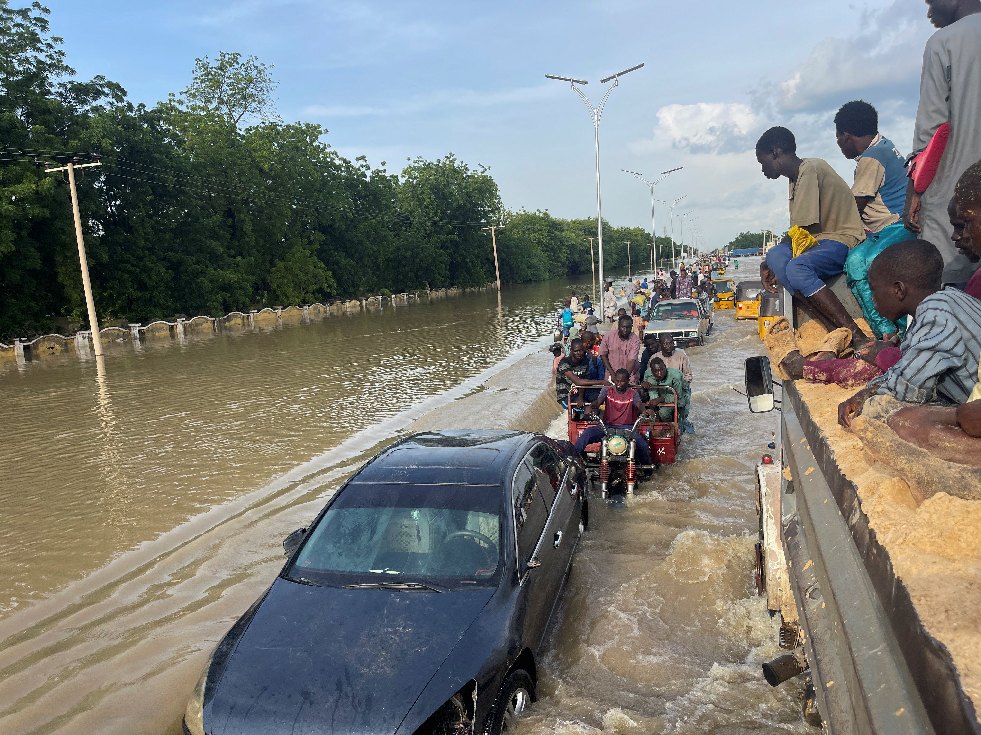 Residents leave the flooded areas with their belongings in Maiduguri
