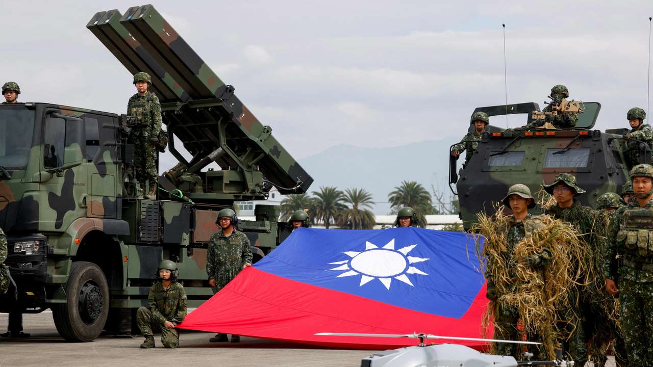 Taiwanese soldiers pose with a Taiwanese flag near a Sky Sword II surface-to-air missile launcher and a military UAV during an annual military exercise ahead of Lunar New Year in Taichung