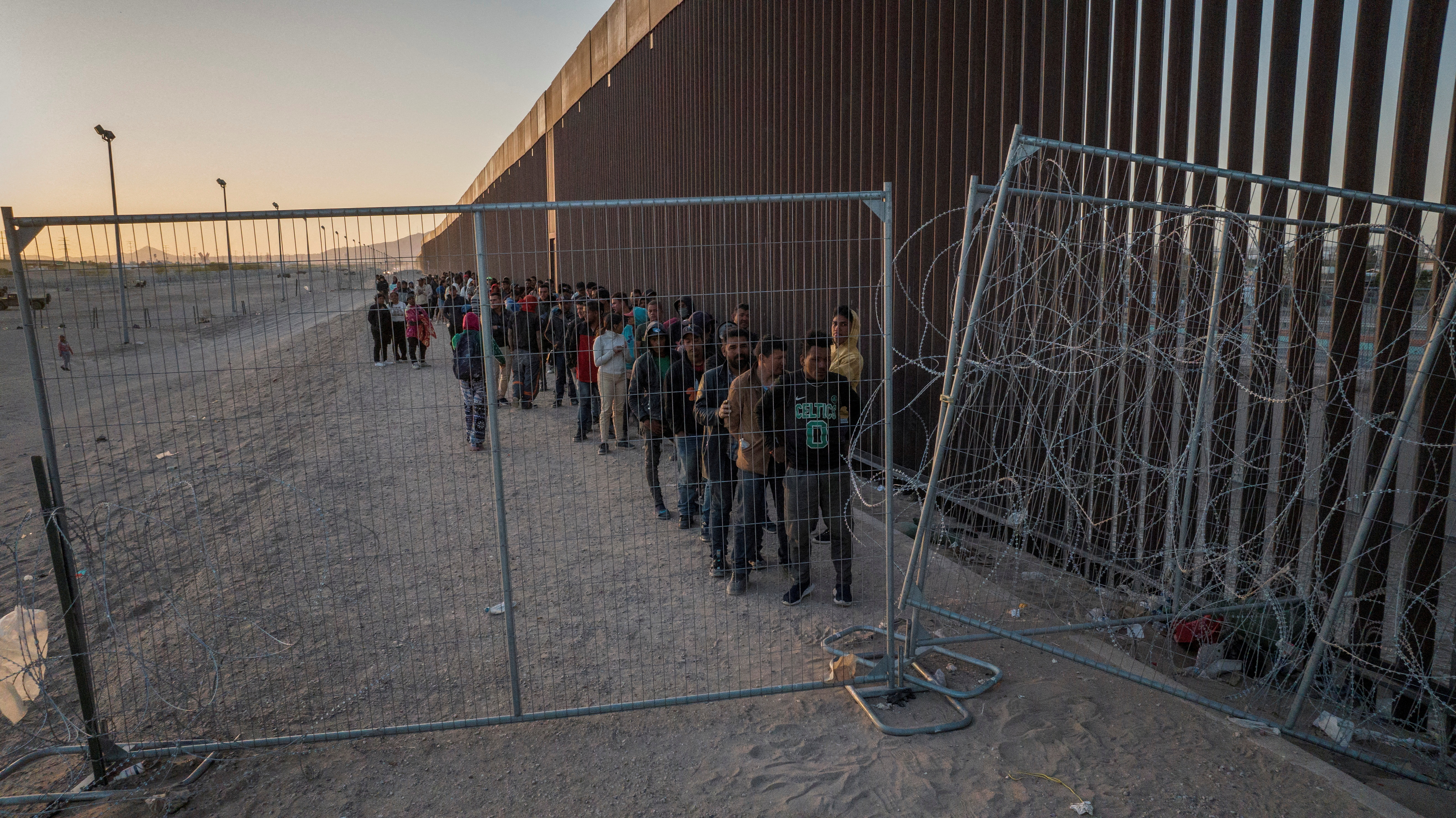 Migrants line up against border wall to surrender in El Paso