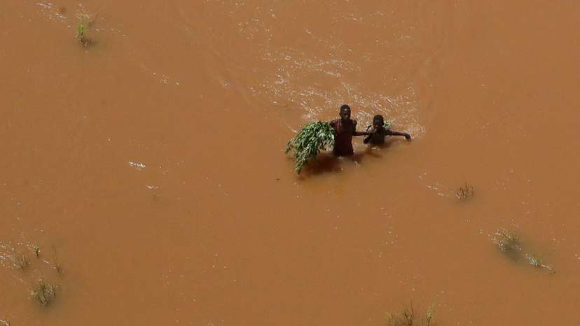 FILE PHOTO: People hold on to plants as they wade through flood waters after they were displaced following heavy rains in Garsen
