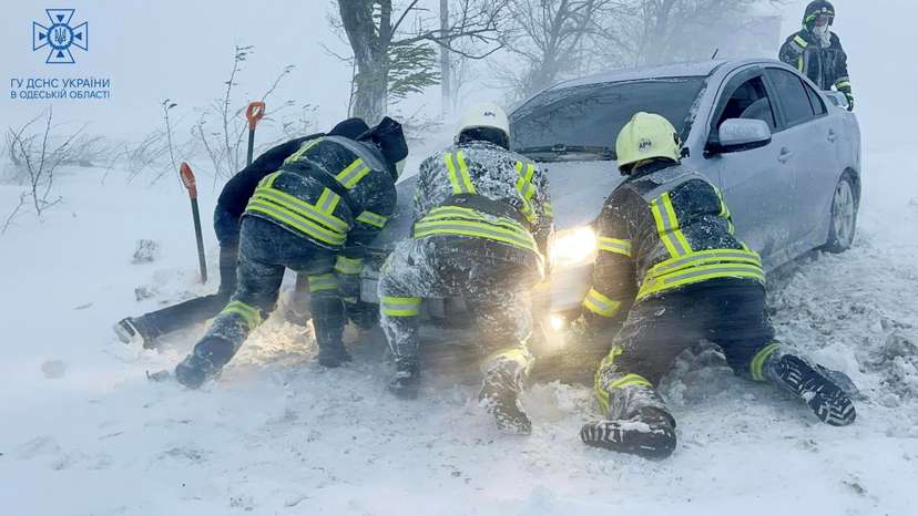 Emergency workers release a car which stuck in snow during a heavy snow storm in Odesa region