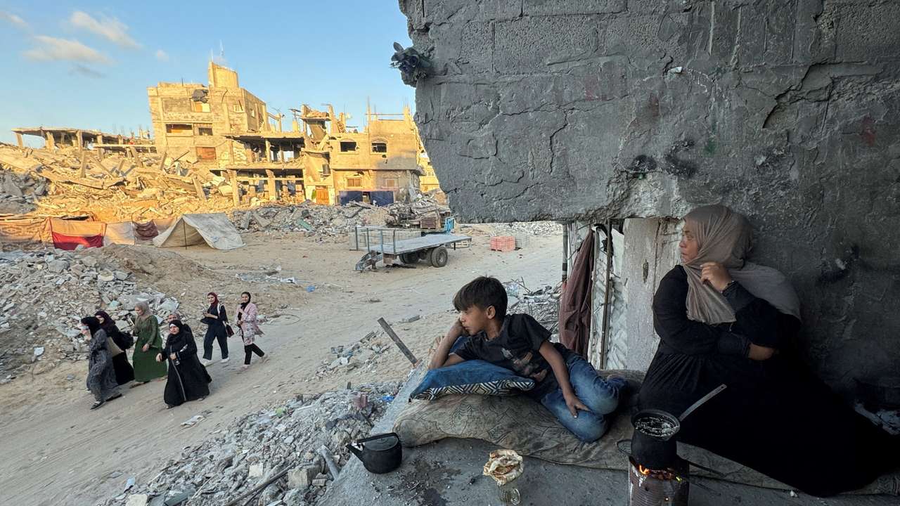 Palestinians sit at their houses, destroyed in Israeli strikes, in Khan Younis