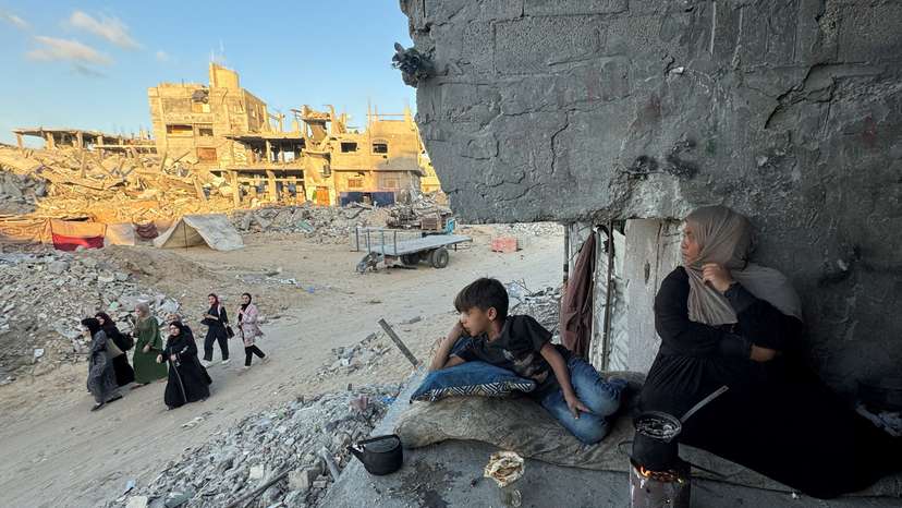 Palestinians sit at their houses, destroyed in Israeli strikes, in Khan Younis