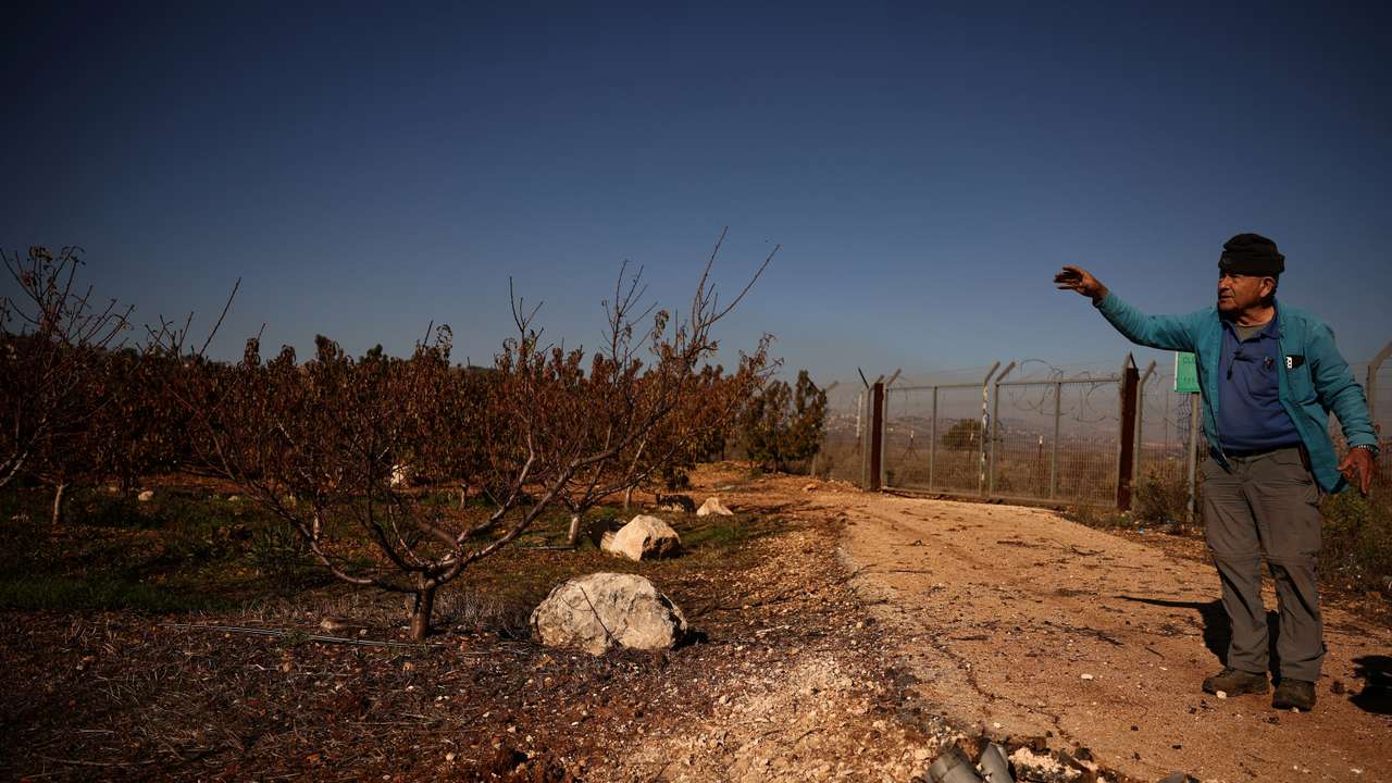 Moshe Weinstein, 76, an Israeli farmer stands near the remains of a rocket, launched from Lebanon, at his apple farm in Metula