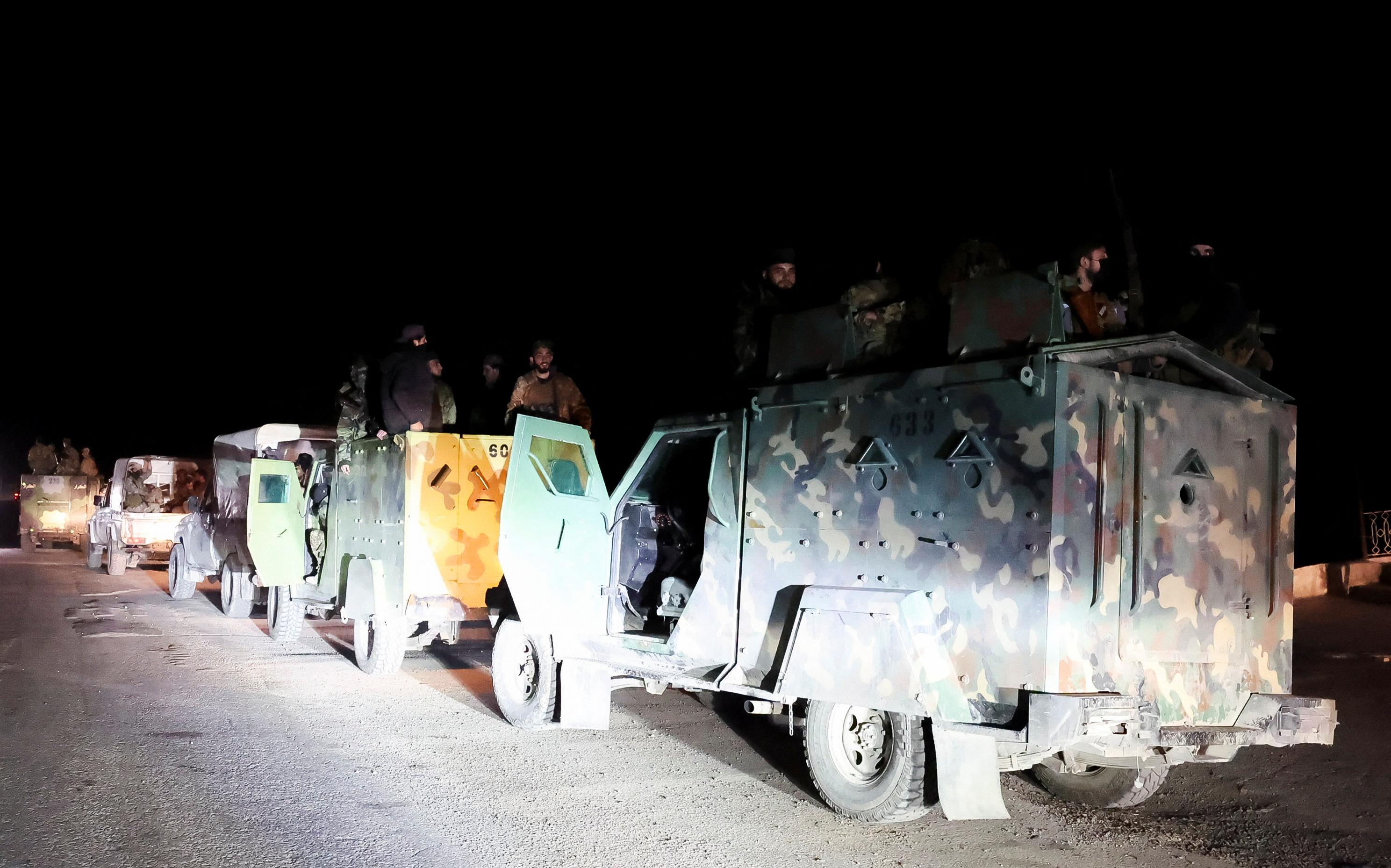 Syrian forces ride on military vehicles as they head to Latakia, in Aleppo