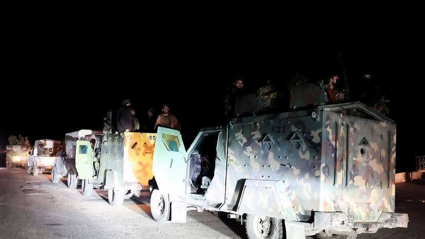Syrian forces ride on military vehicles as they head to Latakia, in Aleppo