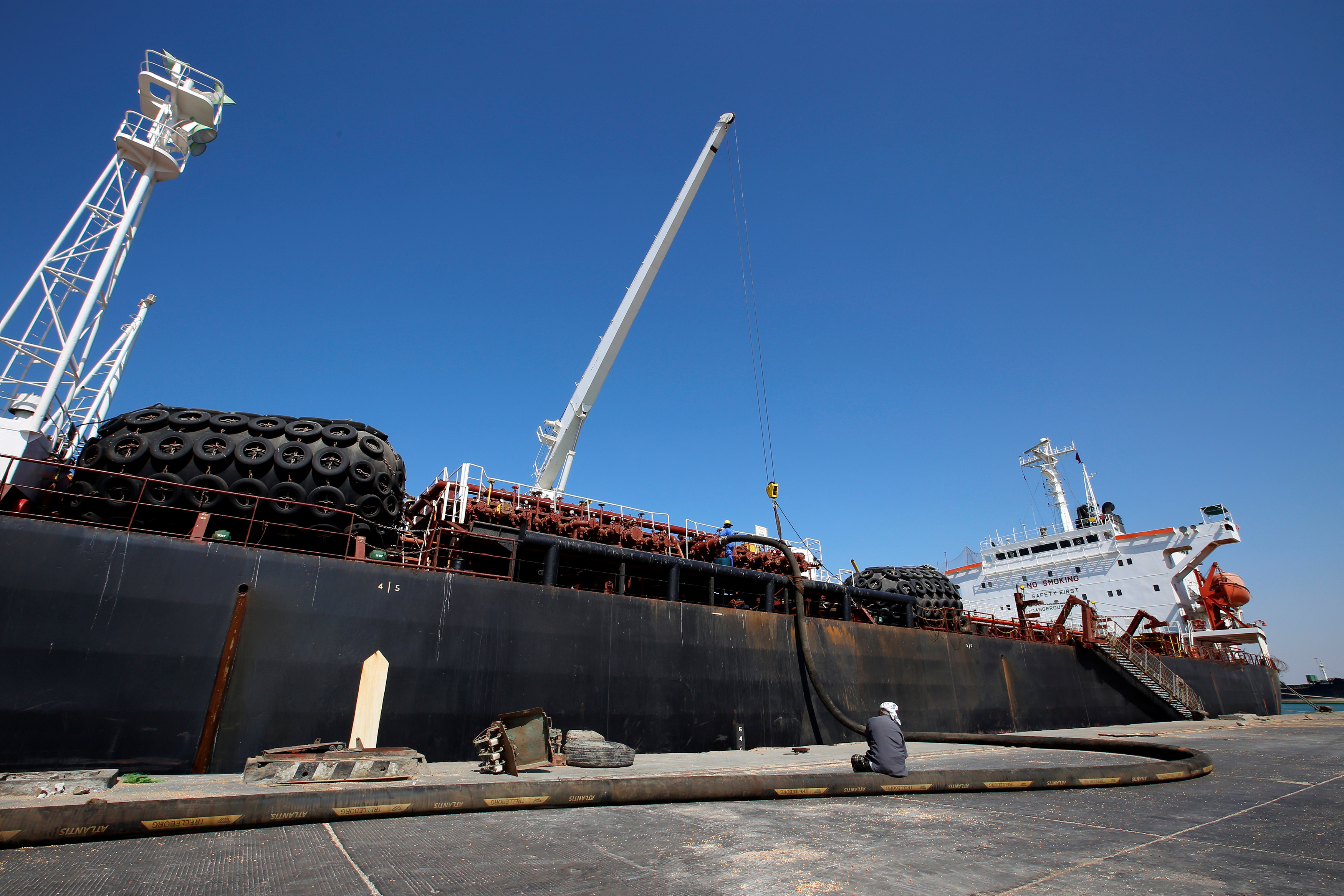 Worker sits next to fuel tanker Bahia Damas as it unloads its shipment of fuel at the Red Sea port of Hodeida, Yemen