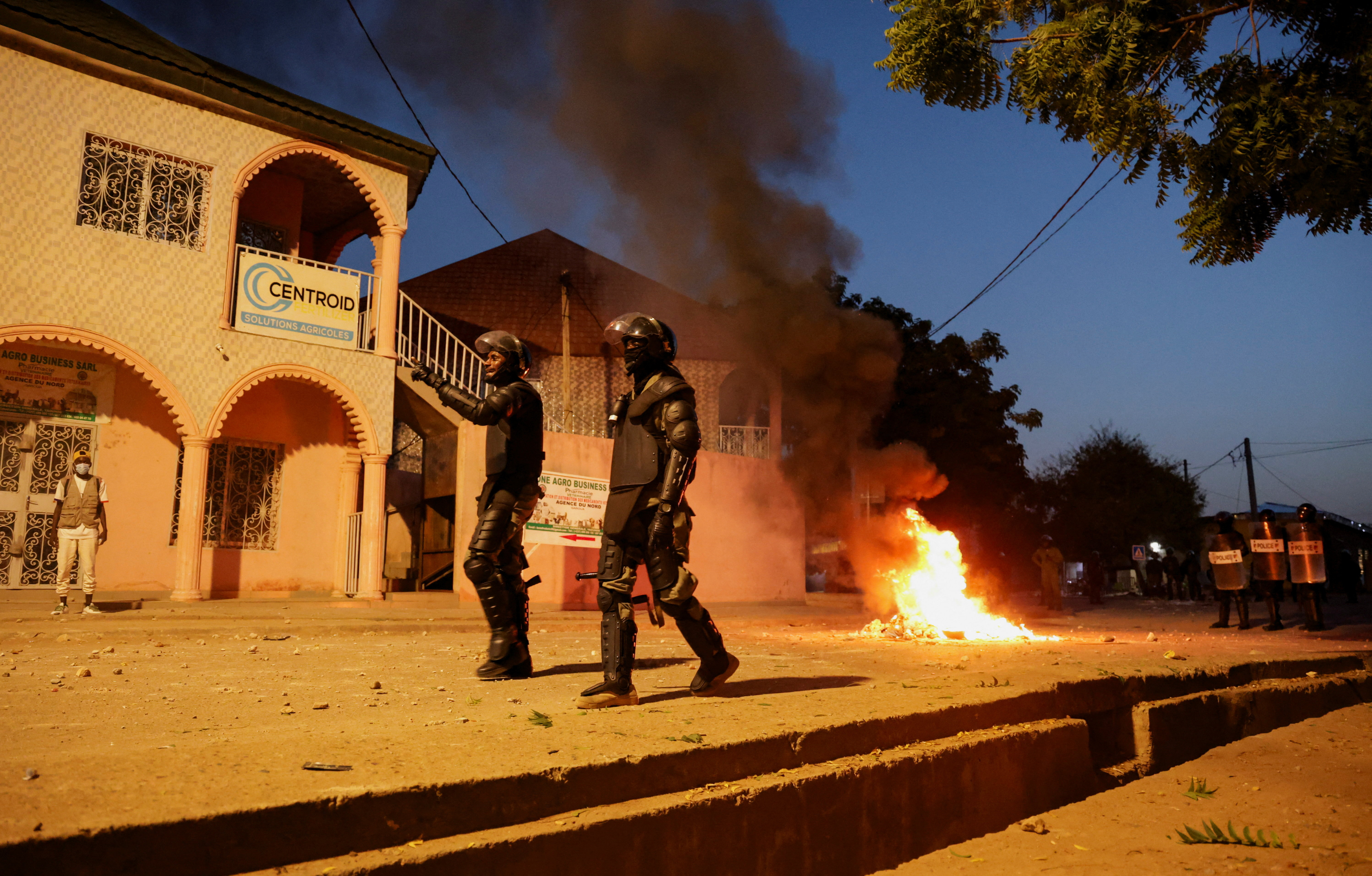 Police wearing body armour walk on a street as a fire burns during clashes with supporters of Cameroon opposition leader Issa Tchiroma Bakary in Garoua, Cameroon