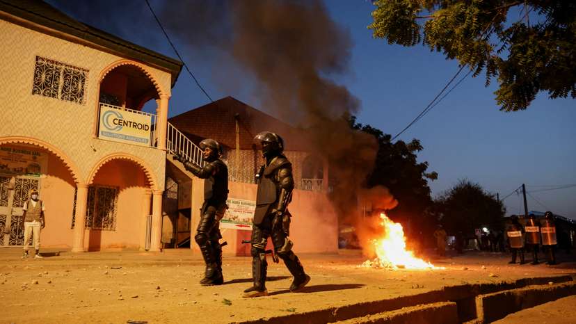 Police wearing body armour walk on a street as a fire burns during clashes with supporters of Cameroon opposition leader Issa Tchiroma Bakary in Garoua, Cameroon
