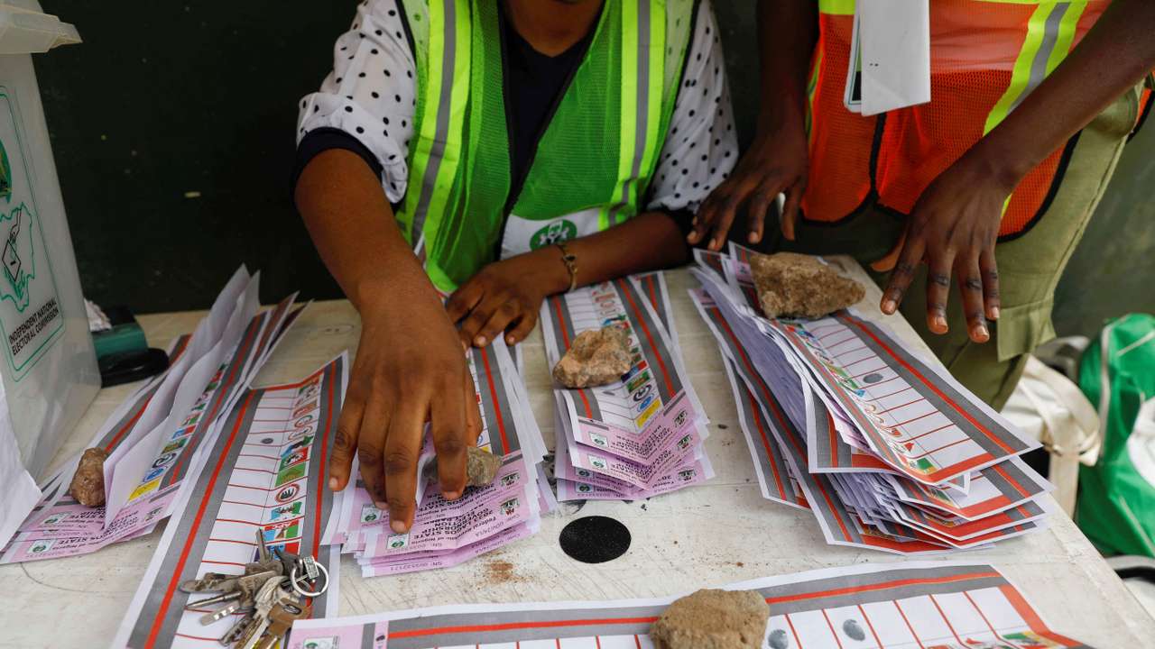 Electoral officials use stones to hold down ballots during the vote counting process of the gubernatorial election, in Lagos