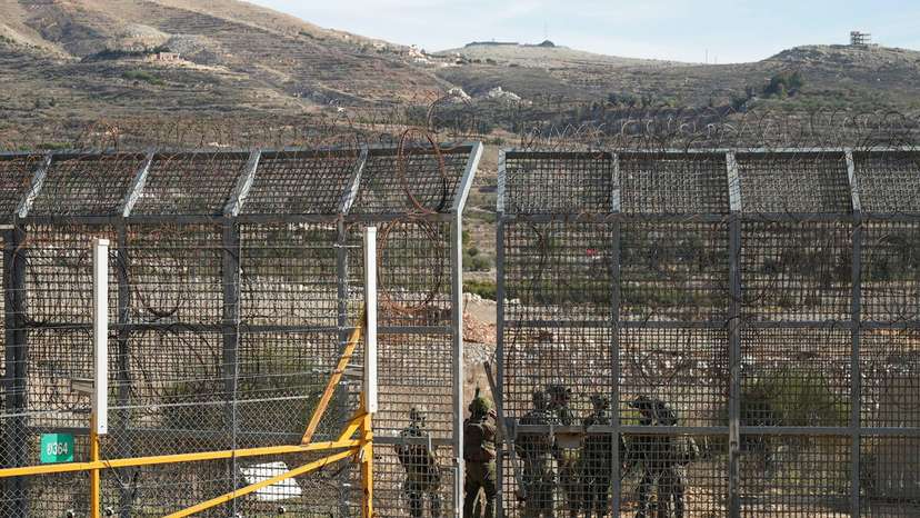 Israeli soldiers syand on the Syrian side of the ceasefire line between Syria and the Israeli-occupied Golan Heights, as seen from the Golan Heights