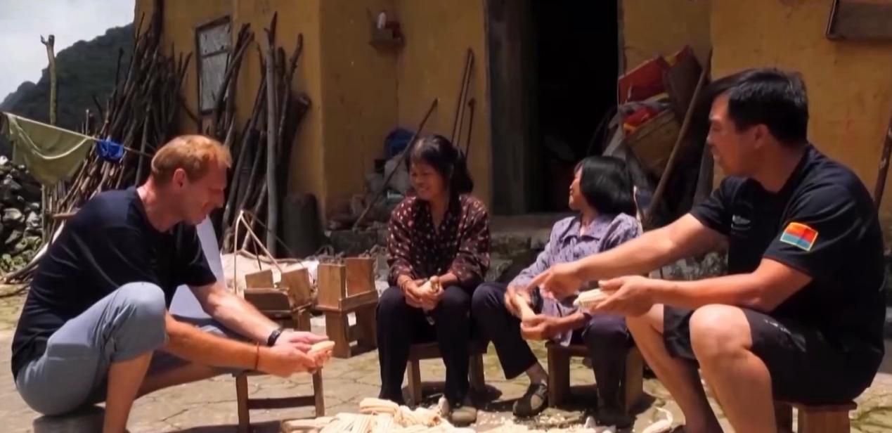Hansen (Left) helps villagers to shuck corn in Lianhua Village in Guangxi. 