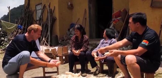 Hansen (Left) helps villagers to shuck corn in Lianhua Village in Guangxi.