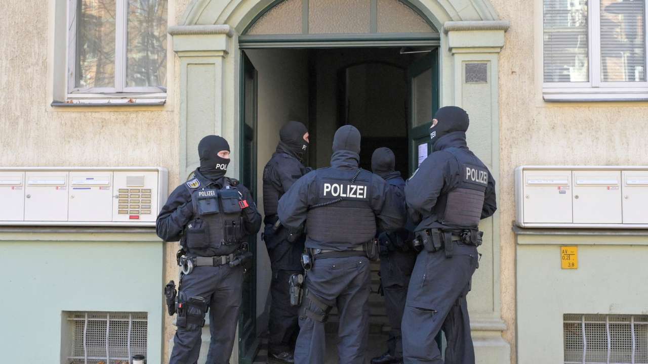 Masked German police officers guard a house in Dresden