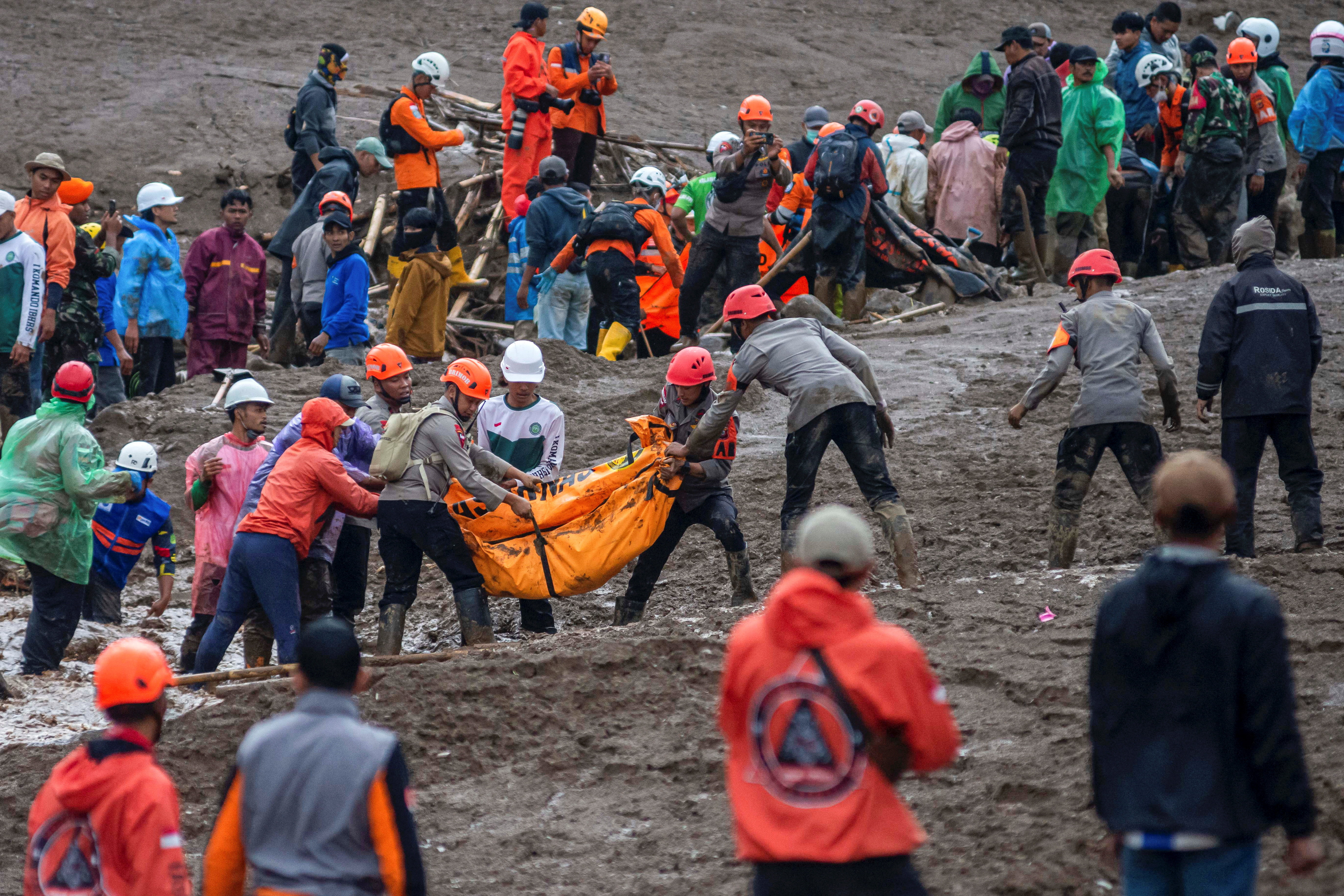 Indonesian rescue members carry a body bag containing the remains of a victim from the site of a landslide after it hit Pasirlangu village, West Bandung