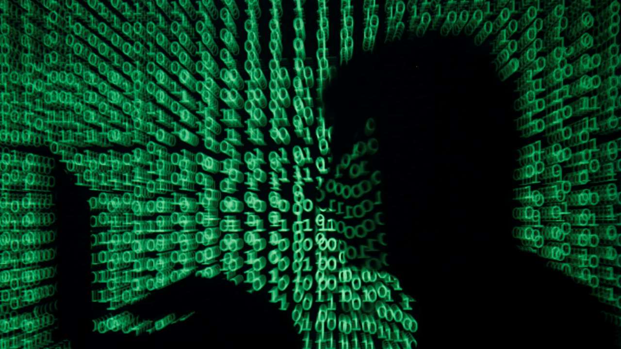 Man holds laptop computer as cyber code is projected on him in this illustration picture