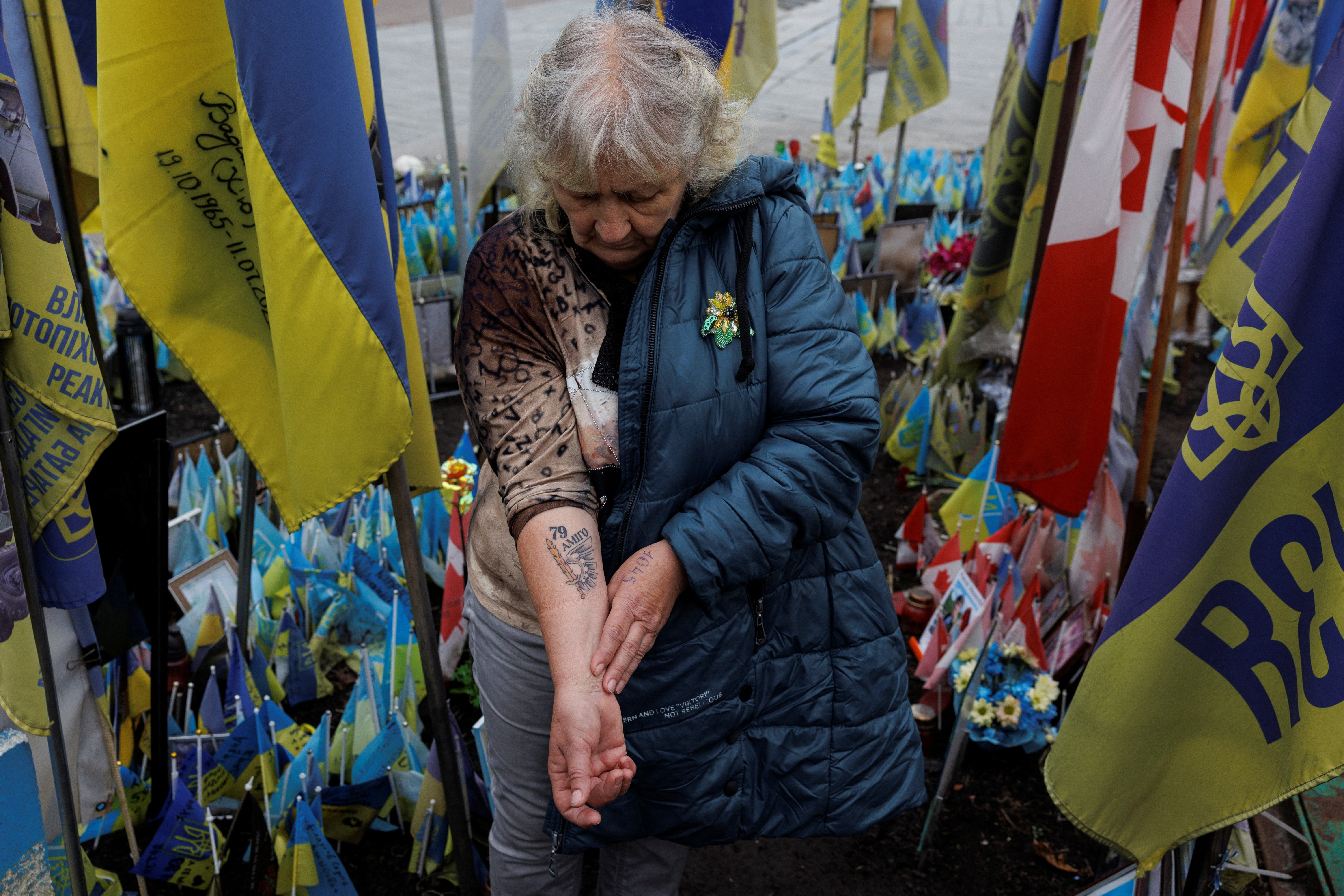 Natalia Lipei shows a tattoo with the call sign of her killed son and the emblem of a brigade where he served, as she visits a makeshift memorial to fallen Ukrainian defenders at the Independence Square in Kyiv