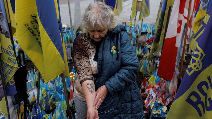 Natalia Lipei shows a tattoo with the call sign of her killed son and the emblem of a brigade where he served, as she visits a makeshift memorial to fallen Ukrainian defenders at the Independence Square in Kyiv