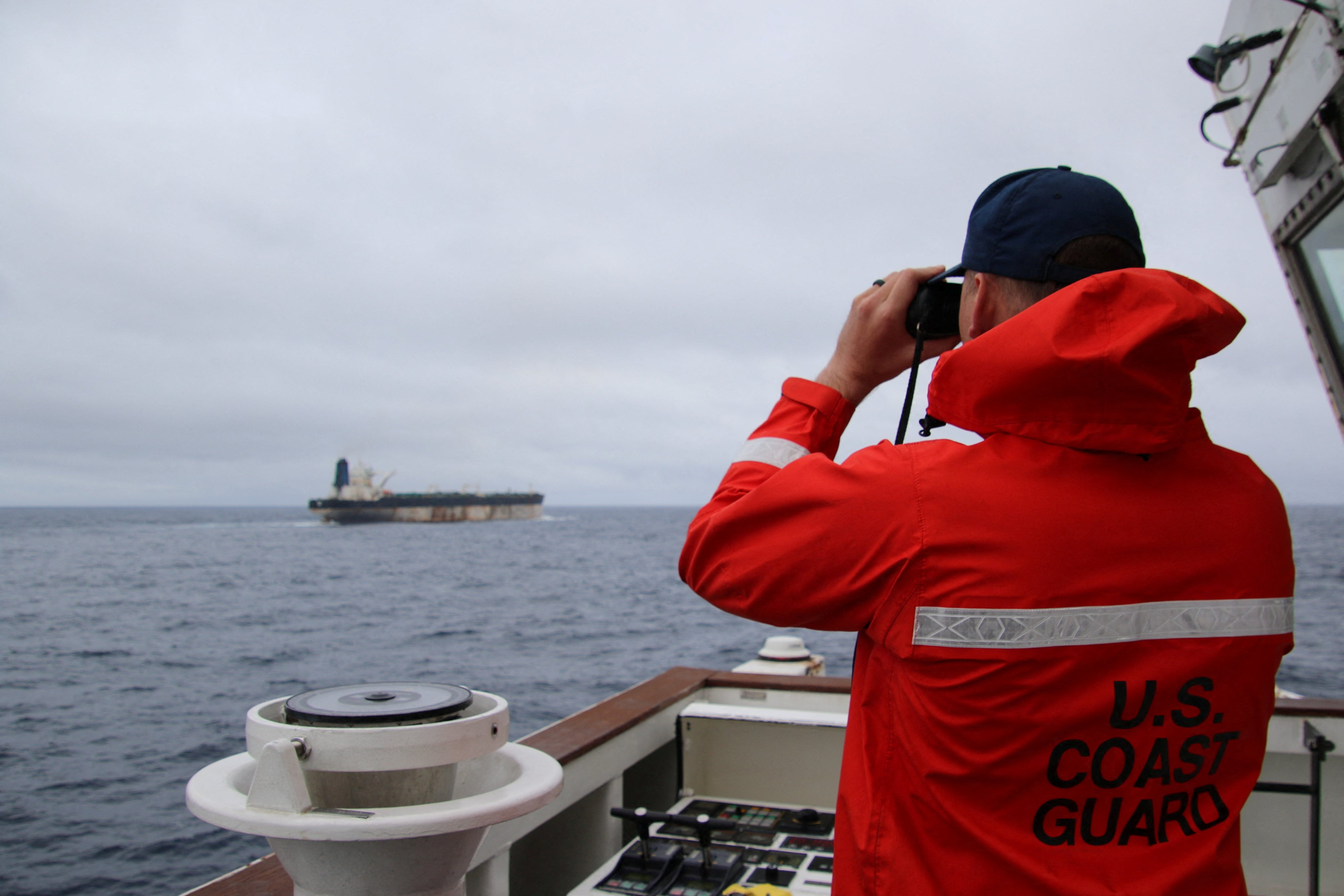 A U.S. Coast Guard official looks through binoculars at the ship Marinera (Ex-Bella 1)