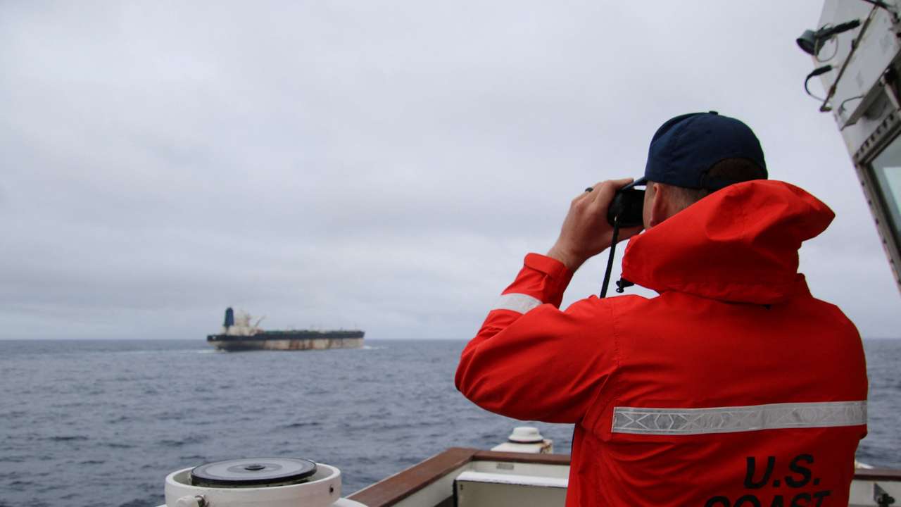 A U.S. Coast Guard official looks through binoculars at the ship Marinera (Ex-Bella 1)