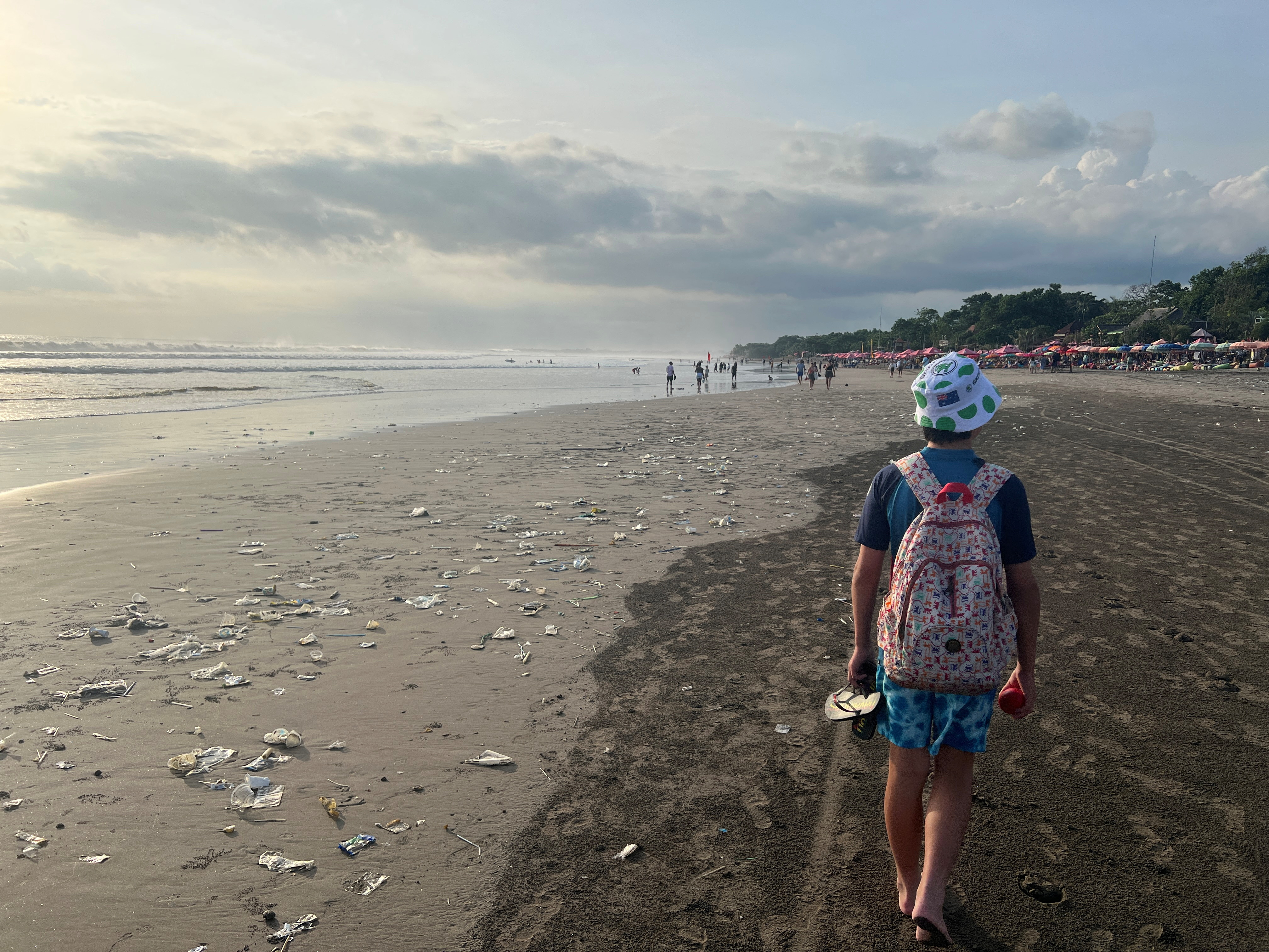 A boy walks on a beach polluted by plastic trash in Bali