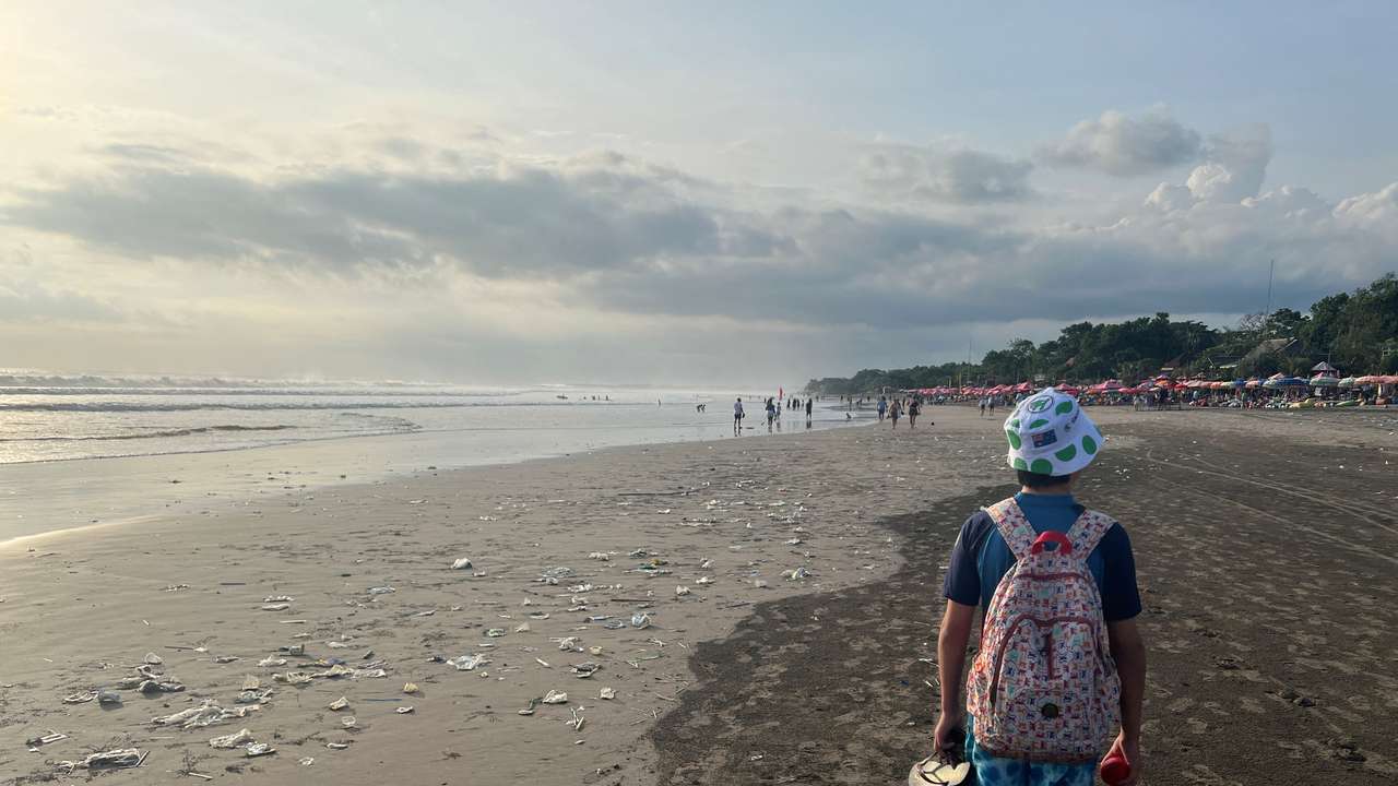A boy walks on a beach polluted by plastic trash in Bali