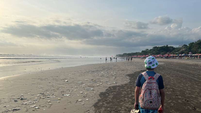 A boy walks on a beach polluted by plastic trash in Bali