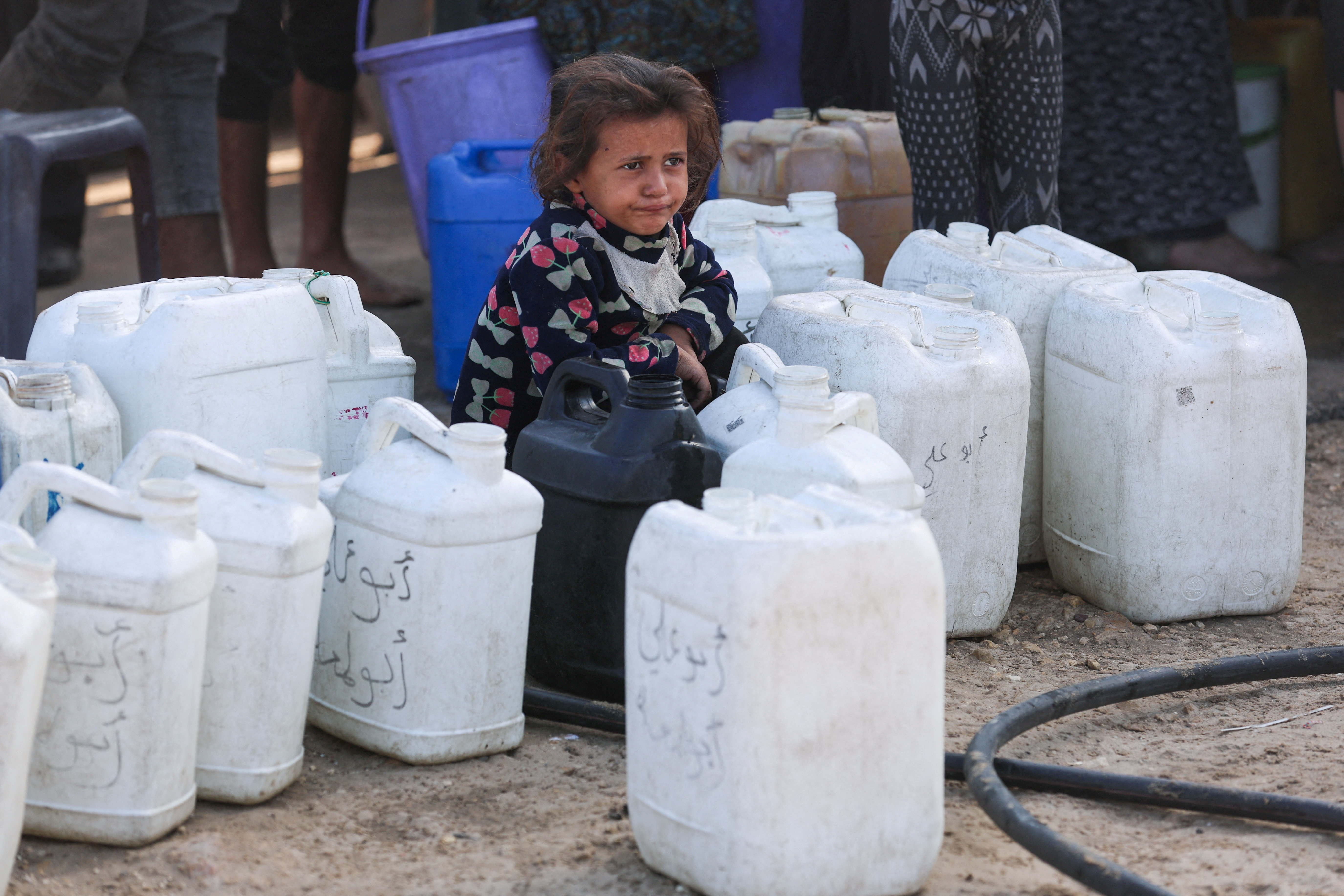 Palestinian child among water containers, in Khan Younis
