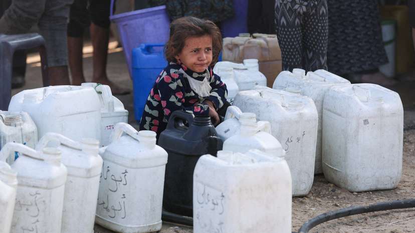 Palestinian child among water containers, in Khan Younis