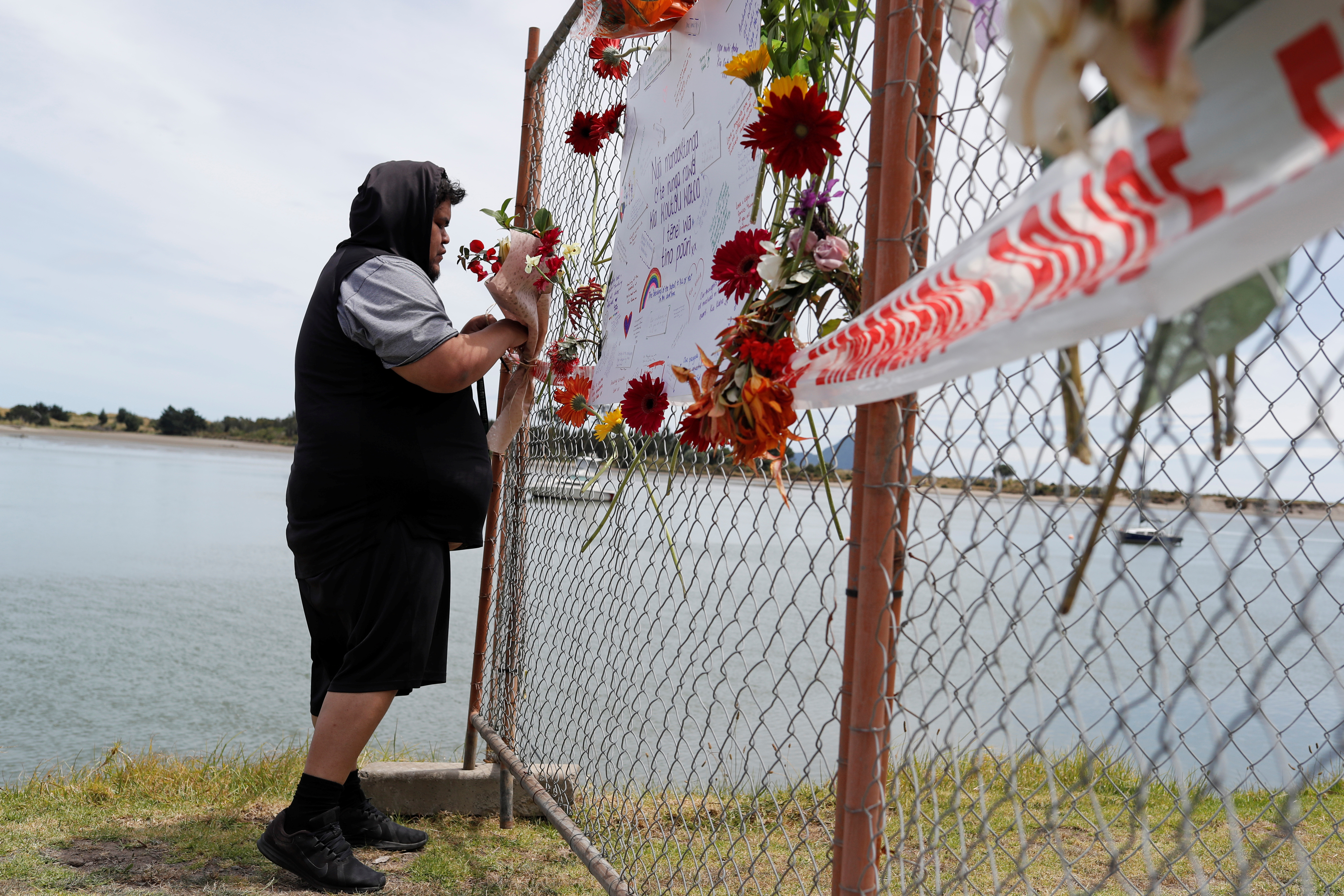 FILE PHOTO: A man offers flowers at a memorial at the harbour in Whakatane, following the White Island volcano eruption in New Zealand