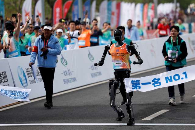 Tiangong Ultra, a humanoid robot runs across the finish line while securing the first position during the E-Town Humanoid Robot Half Marathon, in Beijing, China April 19, 2025. REUTERS/Tingshu Wang