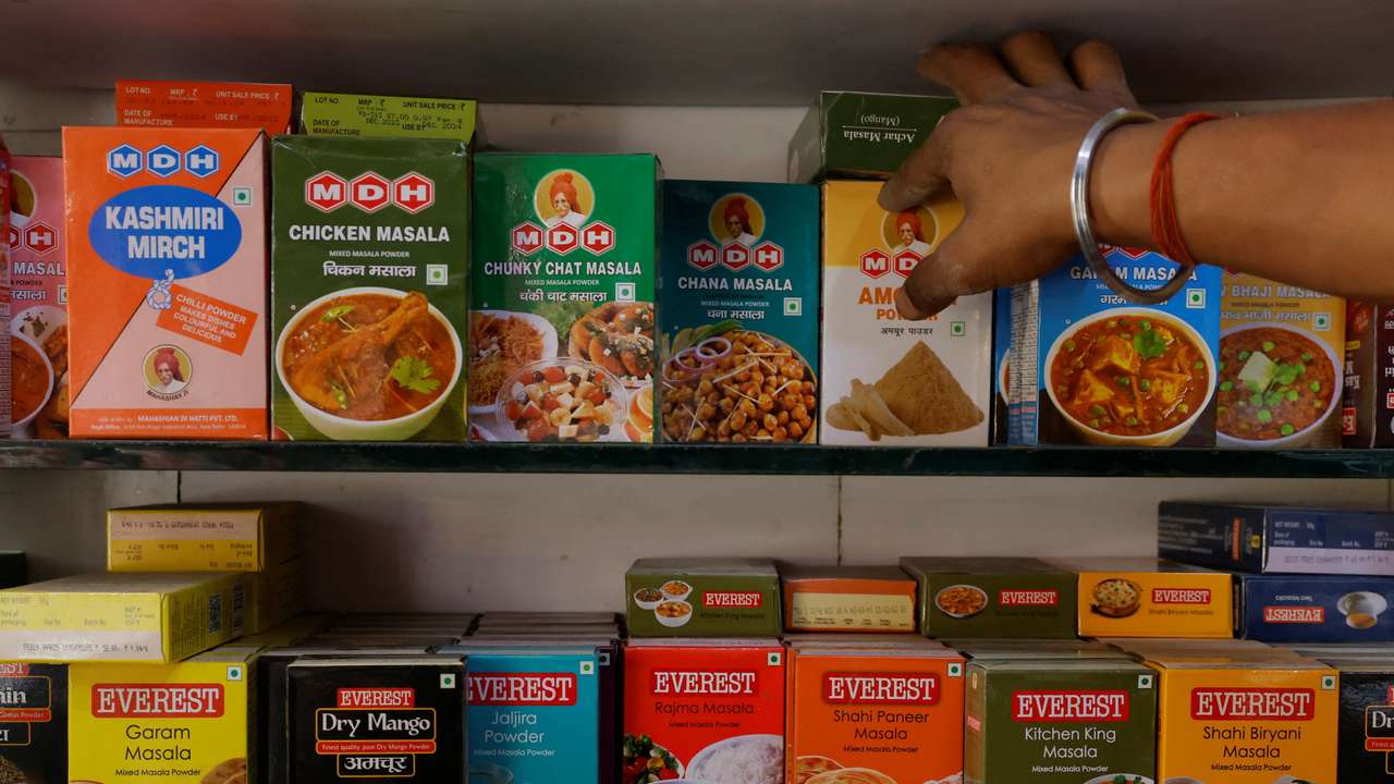 A man adjusts the spice boxes of MDH and Everest on the shelf of a shop at a market in New Delhi